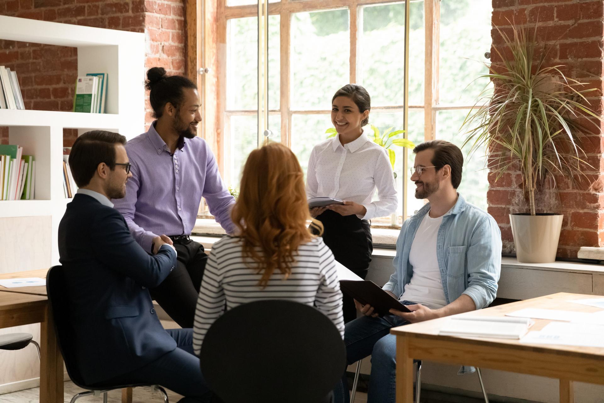 Intersectionality; a group of people sit closely together in a well-lit office space.