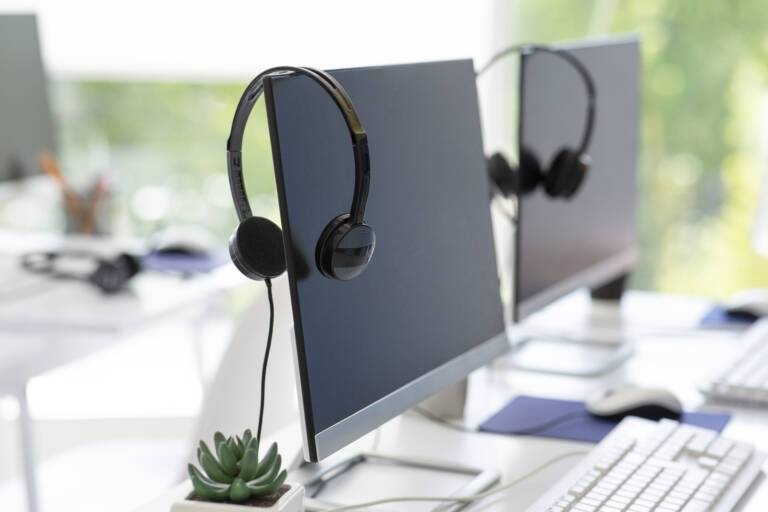 Headsets hang on powered-off computers in an empty office