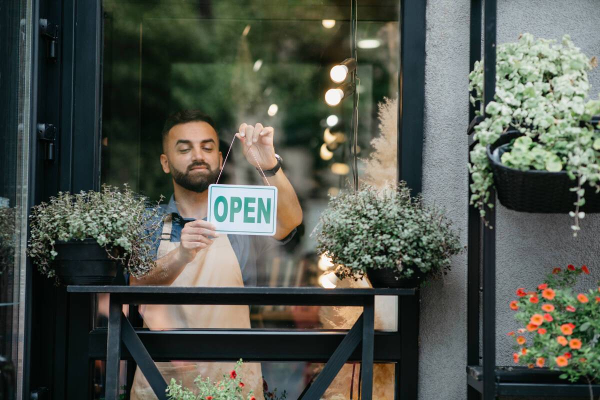 A business owner hangs an "open" sign