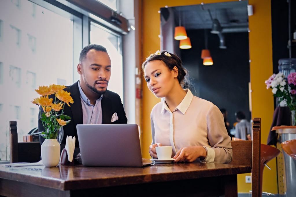 A young couple look at a laptop in a cafe.