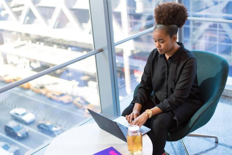 Needs-based selling: woman using laptop in well-lit office next to large window.