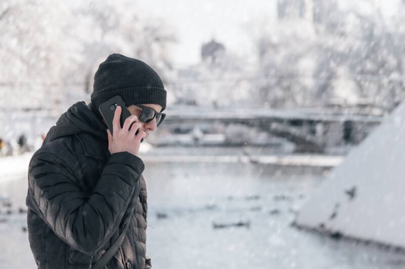 Person talks on phone in snowy outdoor environment