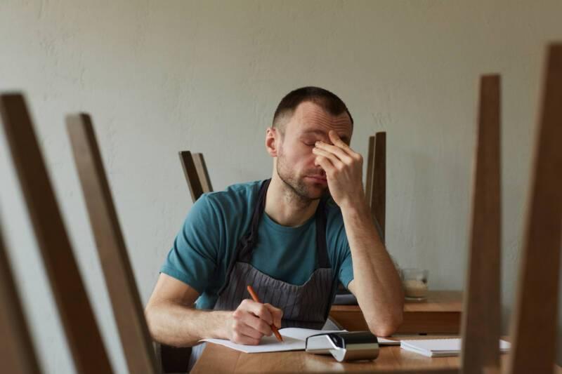 Minimal front view portrait of exhausted business owner calculating finances and doing inventory