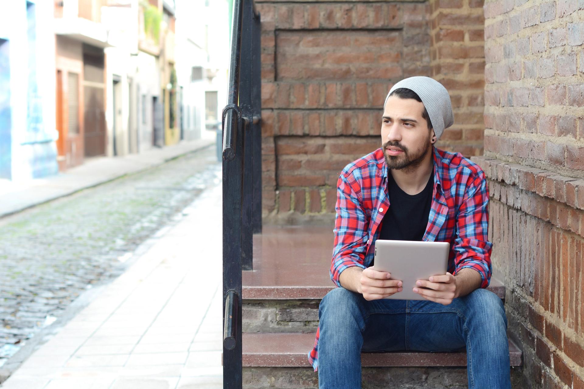 Carlos using a tablet and sitting outside on a sunny day