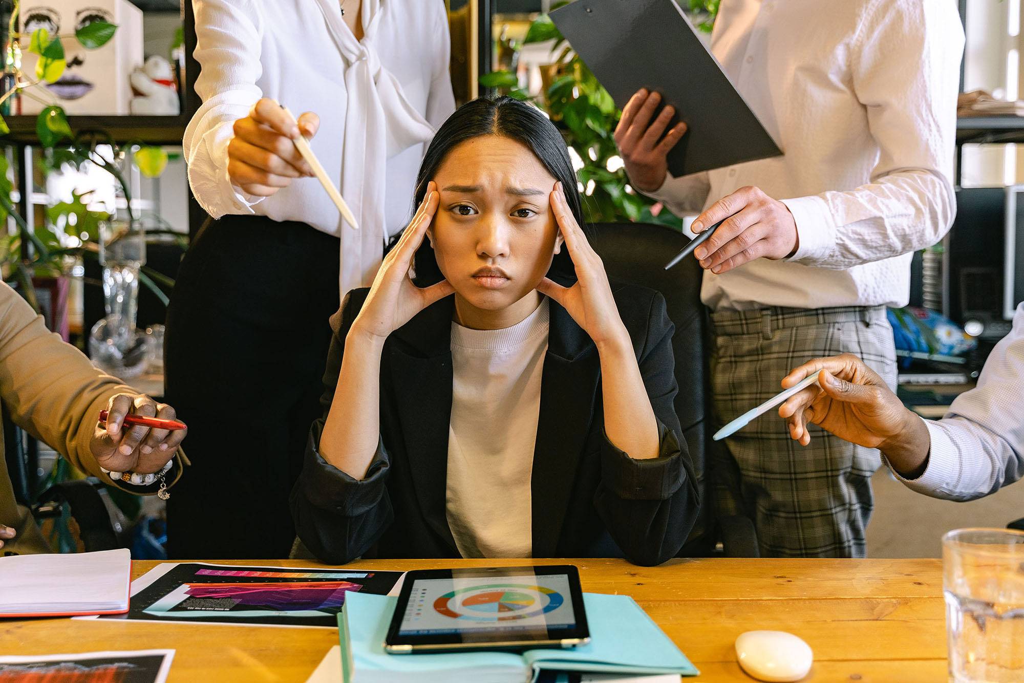 2022 tax season burnout: a finance professional surrounded by demanding people holds her head in her hands