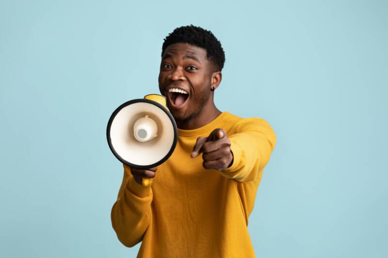 Person speaking excitedly into megaphone and pointing at reader