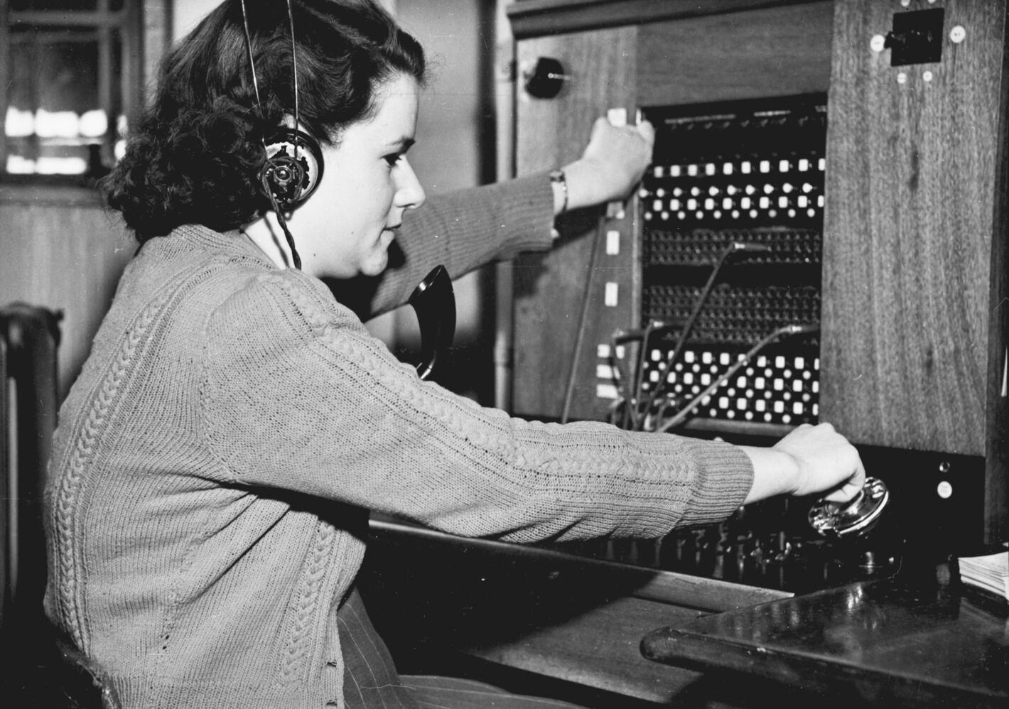 The history of virtual receptionists: black and white photo of a switchboard operator from the mid-20th century