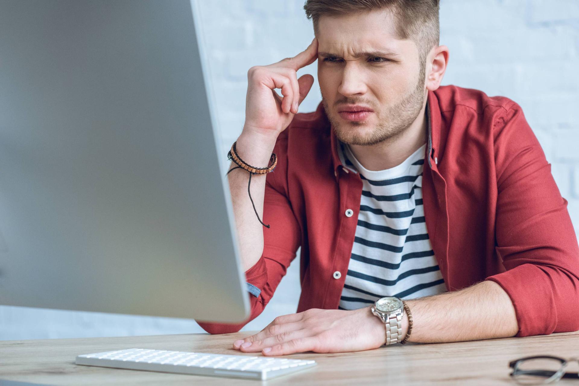 Confused man looks at computer screen