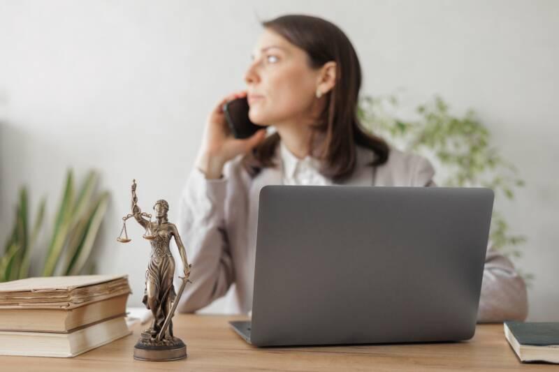 Attorney sits in front of computer and looks away while using phone