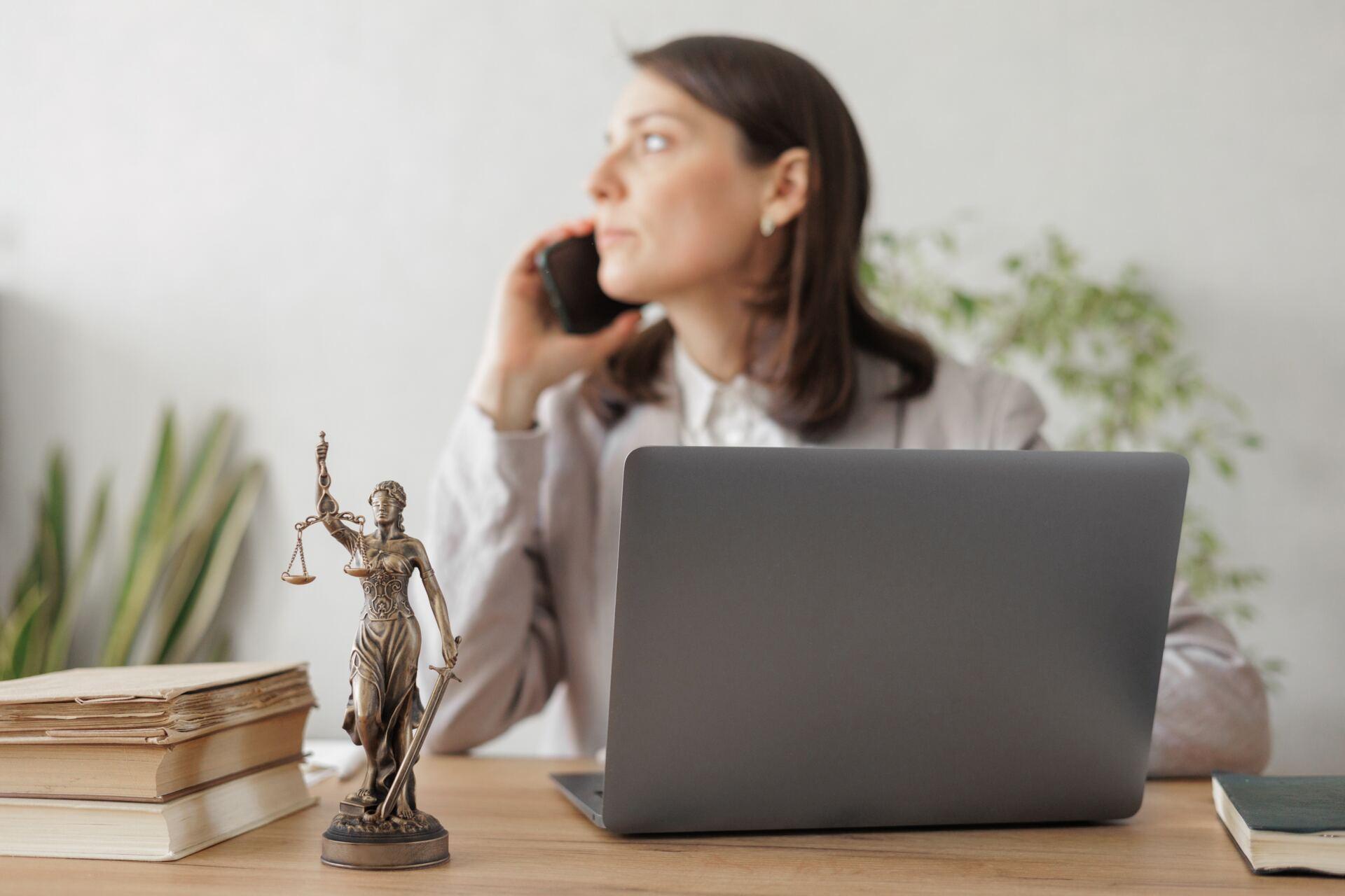 Attorney sits in front of computer and looks away while using phone