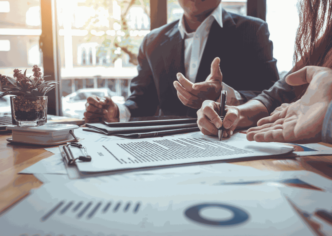 Two business associates chatting and signing paperwork