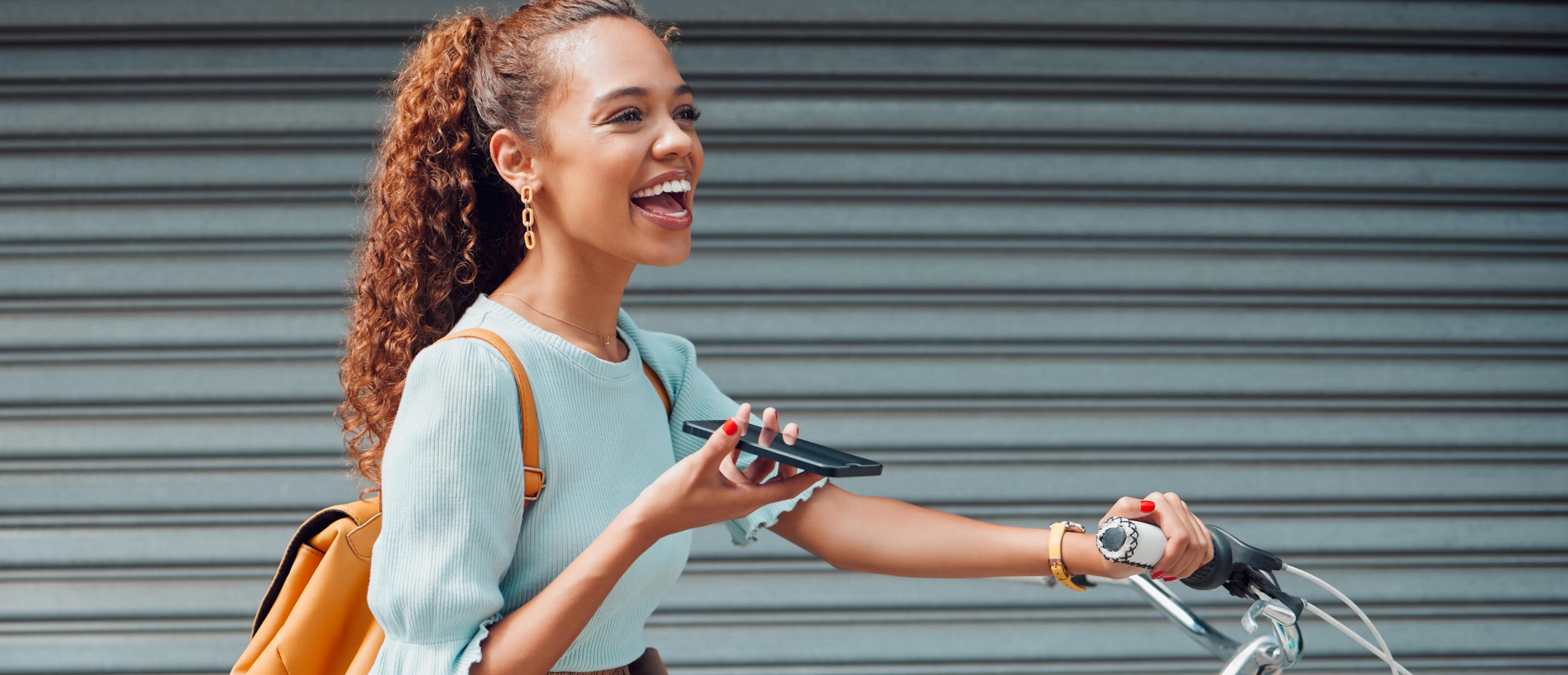 Laughing woman holding phone while on her bike