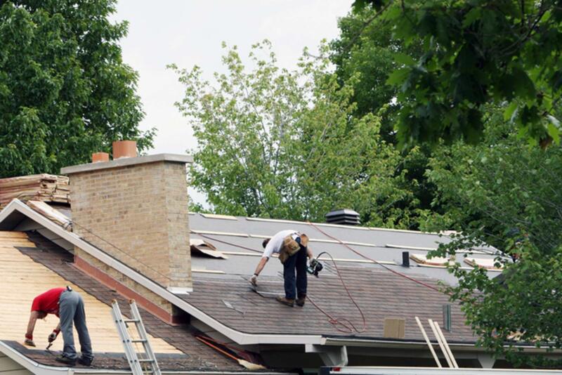 An image of multiple contractors fixing roof shingles