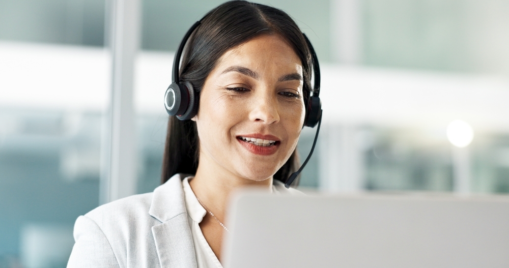 female office worker wearing headset on computer wearing a white shirt